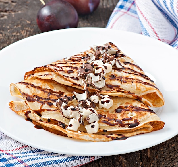 Pancakes with chocolate syrup and plums