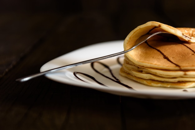 Pancakes with chocolate topping and coffee cappuccino with corica on the table