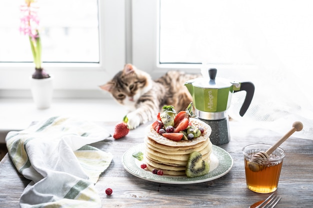 Pancakes with fresh berries and honey, and tea