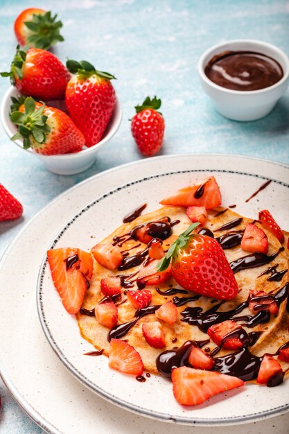 Pancakes with fresh strawberry on a blue wooden wall