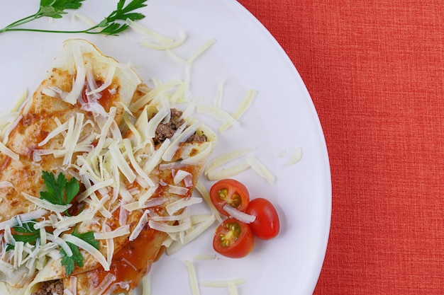 Pancakes with meat, in tomato sauce and cheese, with cilantro and grated cheese on top.