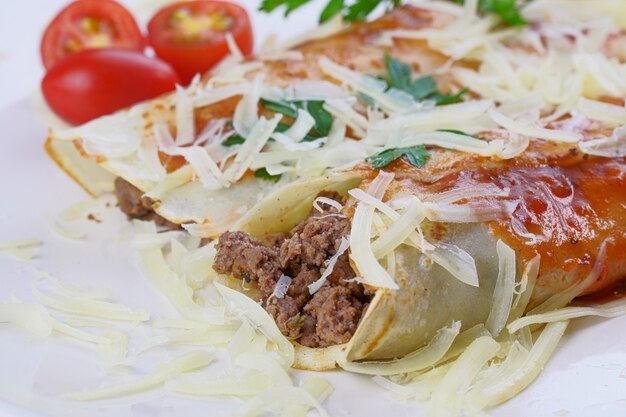 Pancakes with meat, in tomato sauce and cheese, with cilantro and grated cheese on top.