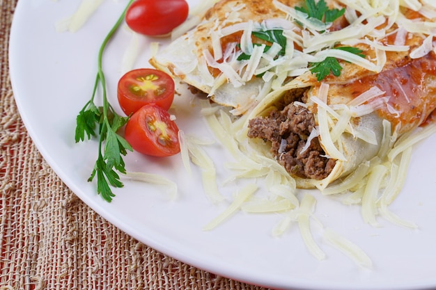 Pancakes with meat, in tomato sauce and cheese, with cilantro and grated cheese on top.