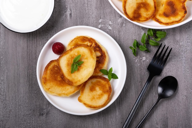 Pancakes with sour cream on a gray wooden table