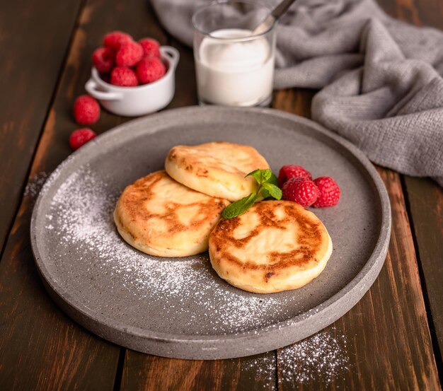 Pancakes with sour cream and raspberry jam on a plate