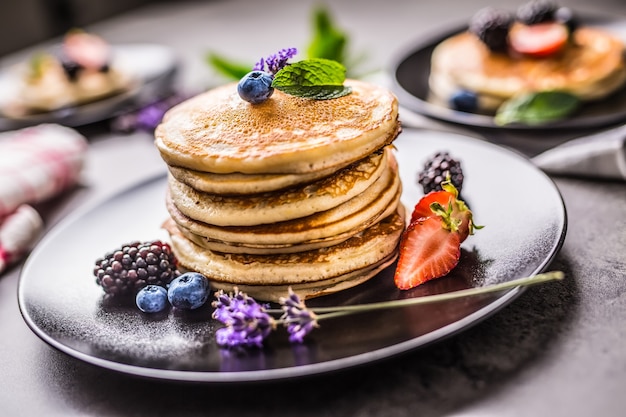 Pancakes with strawberries blackberries blueberries levander and mint leaves.