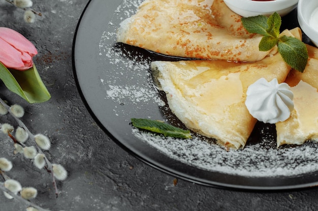 Pancakes with strawberries and creme black plate