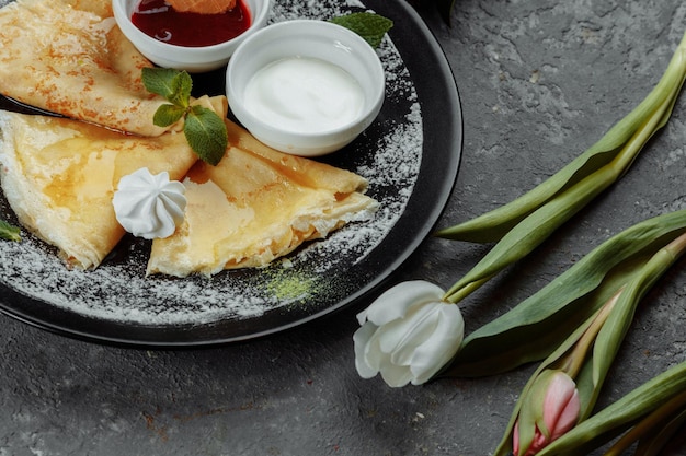 Pancakes with strawberries and creme black plate