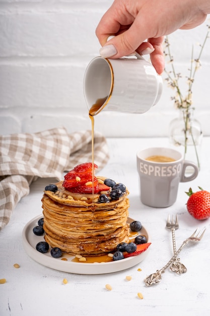 Pancakes with syrup and berries on a breakfast table