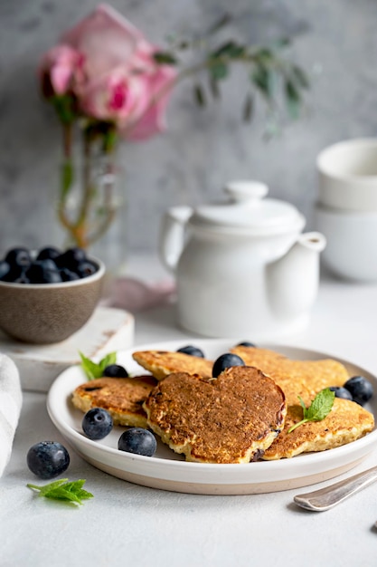 Pancakesheart shaped with fresh blueberries Morning breakfast delicious vegan pancakes Bright background