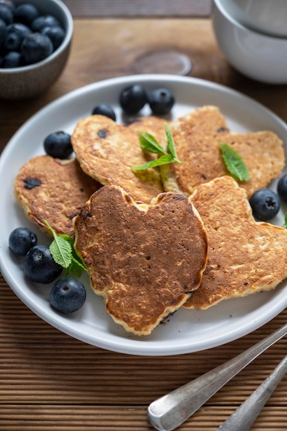 Pancakesheart shaped with fresh blueberries Morning breakfast delicious vegan pancakes Rustic woodenbackground