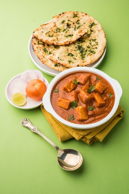 Paneer Butter Masala or Cheese Cottage Curry, popular Indian Lunch and Dinner menu  served in Karahi with Naan Or Roti over moody background, selective focus