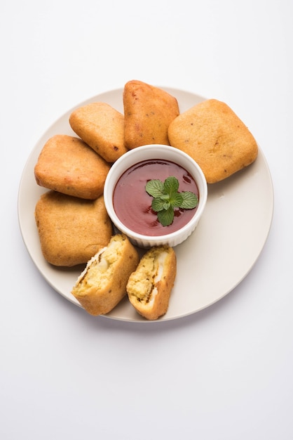 Paneer pakoras or Bhajji are gram flour or besan batter coated spicy Cottage Cheese cubes. Served with tomato Ketchup in a plate over colourful or wooden background. Selective focus