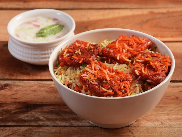 Paneer tikka Biryani with mixed veggies like Paneer Potato Carrots Peas cooked along with spiced rice and served with onion raita and curry selective focus