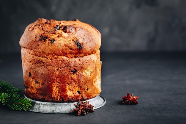 Panettone cake Traditional Italian Christmas cake with dried fruits on dark stone background with copy space