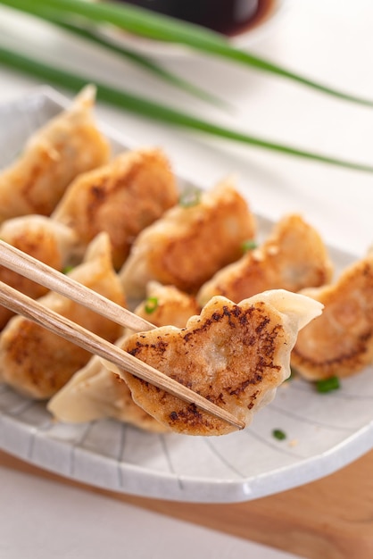 Panfried gyoza dumpling jiaozi in a plate with soy sauce on white table background