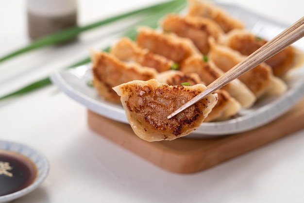 Panfried gyoza dumpling jiaozi in a plate with soy sauce on white table background