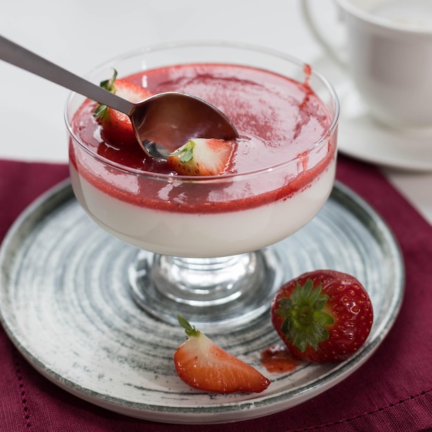 Panna cotta with strawberry sauce and strawberry berries in a bowl on the table and white background