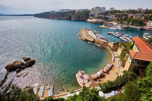 Panorama of Antalya coast from the tall cliff with Mermerli beach Pier of old port modern hotels and Taurus mountains on background