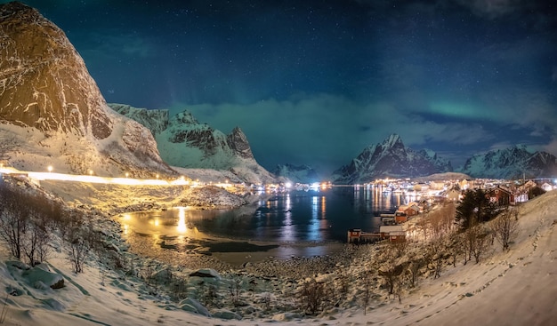 Panorama of Aurora borealis over scandinavian village in winter at night