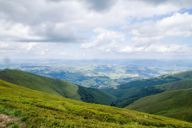 Panorama of green mountains with clouds and village