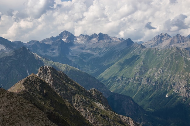 Panorama of mountains scene with dramatic cloudy sky in national park of Dombay, Caucasus, Russia. Summer landscape and sunny day