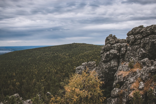 Panorama of mountains scenes in national park Kachkanar, Russia, Europe. Cloudy weather, dramatic blue color sky, far away green trees. Colorful summer day