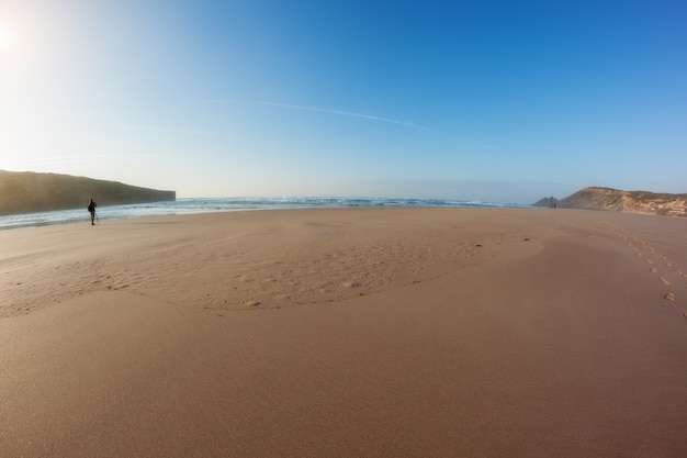 Photo panorama of a sandy beach and a photographer working in front of sea.