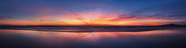 Photo panorama sunset ocean beach of spain city tarifa andalusia. atlantic ocean waves background bright magic sunset sky