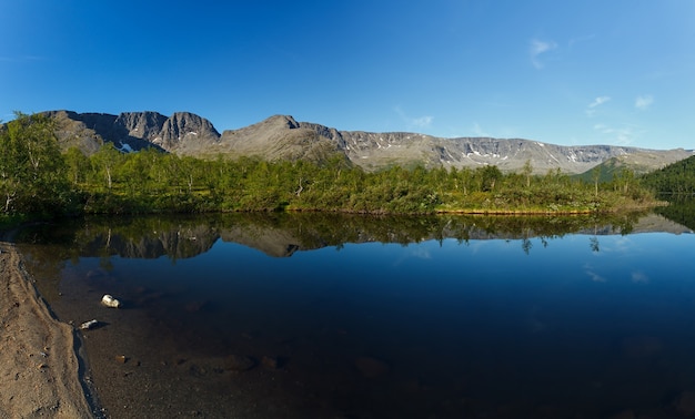 Panorama with the mountains of the Khibiny, sky reflected in the lake Small Vudyavr. Kola Peninsula, Russia.