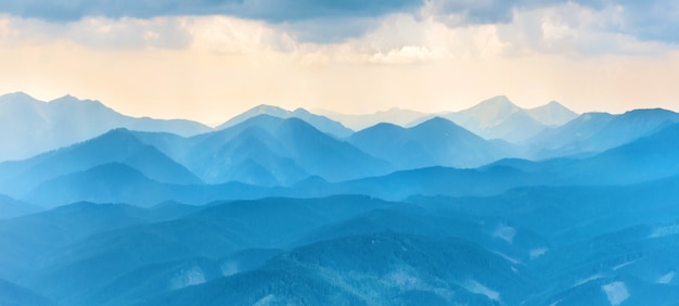 Panorama with sunset in blue mountains. Landscape view of peaks ridge