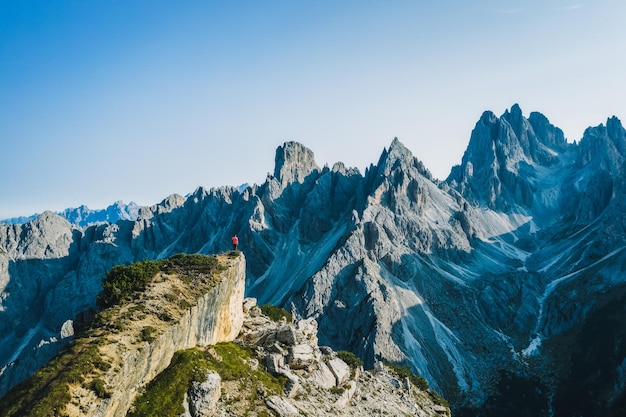 A panoramic aerial view of a man on the top enjoying epic Cadini di Misurina mountain peaks Italian