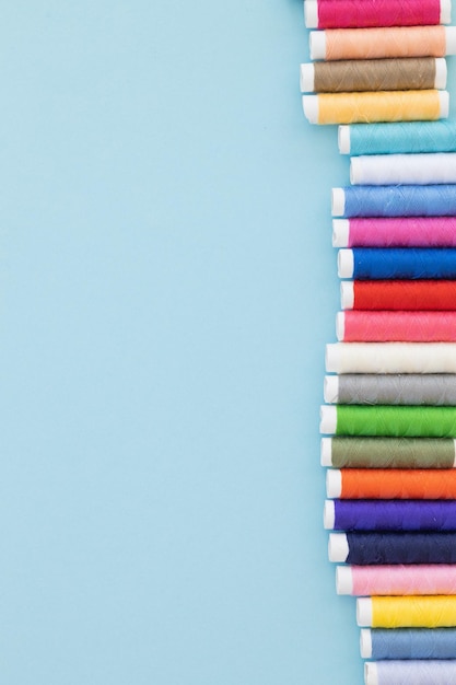 Panoramic detailed view of multi colored spools of thread on a blue background