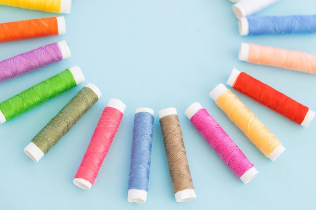 Panoramic detailed view of multi colored spools of thread on a blue background