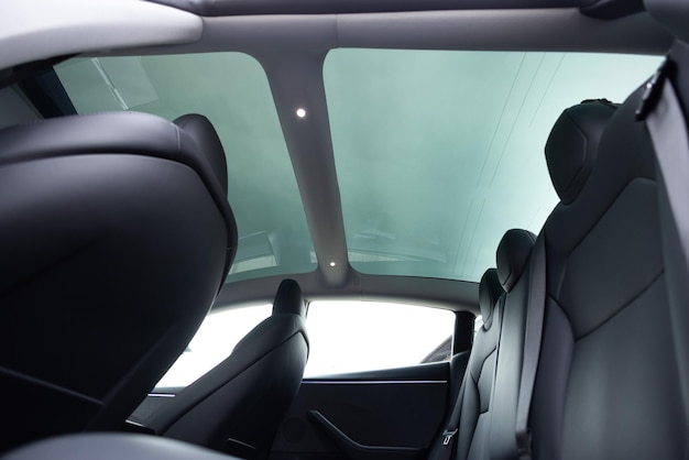 Panoramic glass sun roof in the modern electric car Clean sunroof and view at the sky