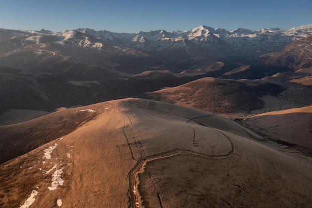 Panoramic landscape with hills gradually turning into snowcovered rocky mountains Caucasus Russia