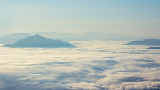 Panoramic natural view of rang of mountain and green tree cover with sunrise morning fog with dramatic beauty nature sky.