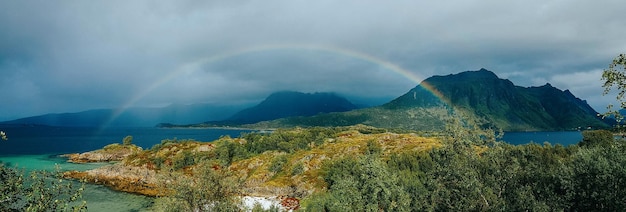 Panoramic photo of rainbow sea hills blue sky in Norway on summer