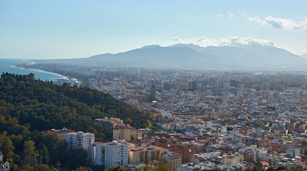 A panoramic shot of a breathtaking view of a coastal town surrounded by incredibly tall and slender mountains