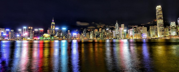 Photo panoramic shot of illuminated city skyline at victoria harbour