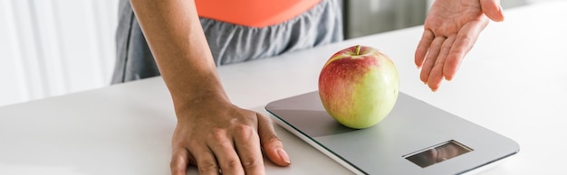 panoramic shot of woman gesturing near food scales and apple