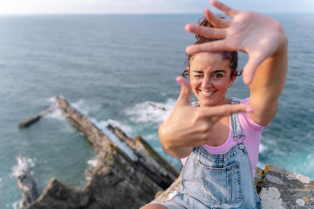 Panoramic top view of woman framing her head with hands like snapshot. Horizontal view of cheerful woman isolated in blue sea in the background. Travel on holidays and people concept.