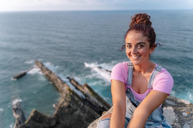 Panoramic top view of woman on holidays in Asturias. Horizontal view of cheerful woman isolated in blue sea in the background. Travel on holidays and people concept.