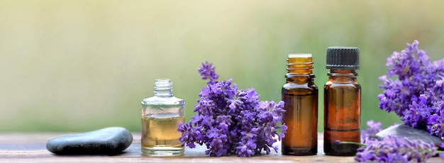 Panoramic view on a bottles of essential oil and lavender flowers arranged on a wooden table on blur background