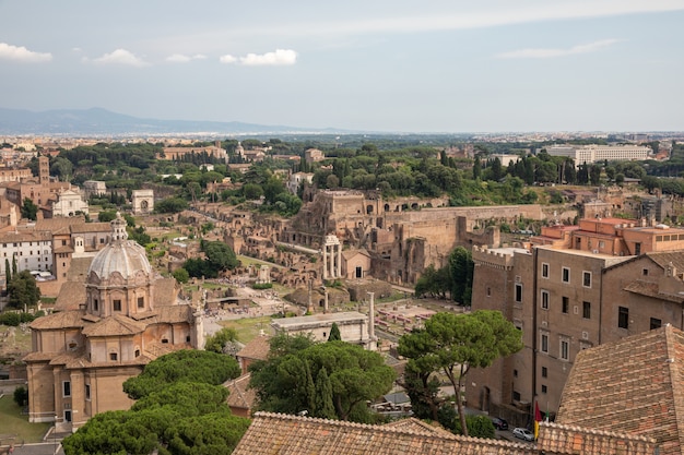 Panoramic view of city Rome with Roman forum and Colosseum from Vittorio Emanuele II Monument also known as the Vittoriano. Summer sunny day and dramatic blue sky