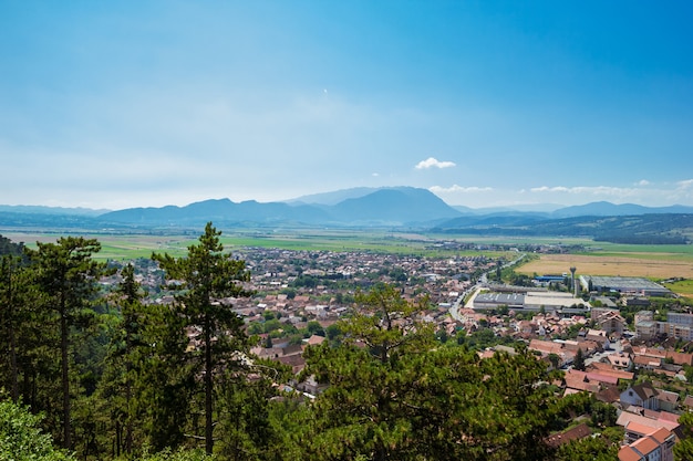 Panoramic view from the top of Rasnov Citadel, Cetatea Rasnov, on the city and Romanian Carpathians mountains in the distance on summer sunny day. Brasov country, Transylvania, Romania