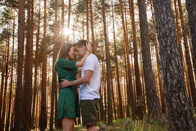 Panoramic view of loving couple kissing at sunset in the forest. Horizontal view of young couple hiking on holidays in nature. Countryside travel and people concept.