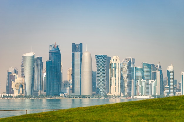 Panoramic view of modern skyline of Doha with green grass foreground. Concept of healthy environment.