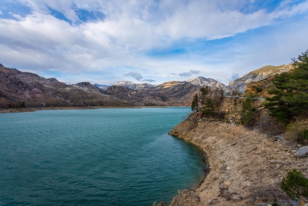 Panoramic view of a mountain lake with clear turquoisegreen water against the background of a road and a village of farmers