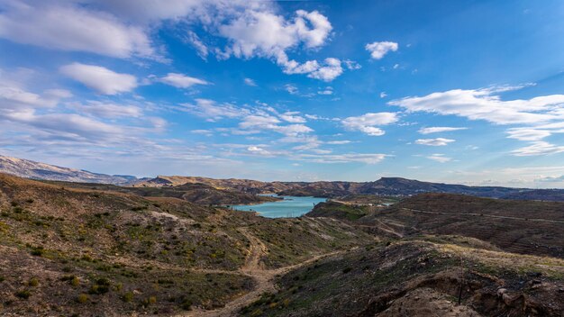 Panoramic view of a mountain lake with clear turquoisegreen water against the background of a road and a village of farmers